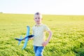 Boy runs with toy airplane in summer through field. Happy child running and playing with toy airplane outdoors. Boy dreams of Royalty Free Stock Photo