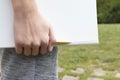 The boy`s hand is holding a notepad with a yellow-black pen in the park against the background of green grass and trees Royalty Free Stock Photo