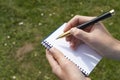 Boy`s hand with a pencil over an open notepad in the park Royalty Free Stock Photo