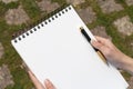 Boy`s hand with a pencil over an open notepad in the park Royalty Free Stock Photo
