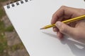 Boy`s hand with a pencil over an open notepad in the park Royalty Free Stock Photo