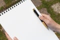 Boy`s hand with a pencil over an open notepad in the park Royalty Free Stock Photo