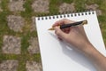 Boy`s hand with a pencil over an open notepad in the park Royalty Free Stock Photo