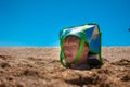 The boy`s head is sticking out of the sand. Wearing a cooler bag on my head