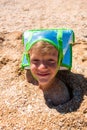 The boy`s head is sticking out of the sand. Wearing a cooler bag on my head