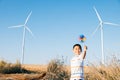 Boy& x27;s playful fascination near wind turbines holding a pinwheel toy Royalty Free Stock Photo