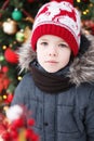 Boy`s portrait outdoors closeup. Blured cristmas tree at background. Blured cristmas tree at background with lights. Royalty Free Stock Photo