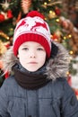 Boy`s portrait outdoors closeup. Blured cristmas tree at background with lights. Royalty Free Stock Photo