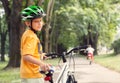 Boy in safe helmet with bicycle in city park