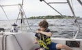 Boy sailing pulling ropes to adjust sails on sailboat