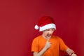 A boy in a Santa Claus Christmas hat holds a gift bag in front of him and shakes his finger Royalty Free Stock Photo