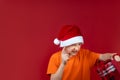 A boy in a Santa Claus Christmas hat holds a gift bag in front of him and shakes his finger Royalty Free Stock Photo