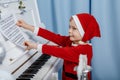 Boy in santa costume. Kid concept for merry Christmas and happy new year celebration. Small boy enjoys playing piano for Royalty Free Stock Photo