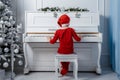 Boy in santa costume. Kid concept for merry Christmas and happy new year celebration. Small boy enjoys playing piano for Royalty Free Stock Photo