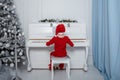 Boy in santa costume. Kid concept for merry Christmas and happy new year celebration. Small boy enjoys playing piano for Royalty Free Stock Photo