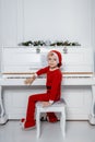 Boy in santa costume. Kid concept for merry Christmas and happy new year celebration. Small boy enjoys playing piano for Royalty Free Stock Photo