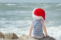 Boy in Santa hat sitting on the beach. Back view Royalty Free Stock Photo