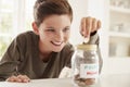 Boy Saving Pocket Money In Glass Jar At Home Royalty Free Stock Photo