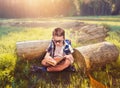 Boy with school bag reading book in yoga pose Royalty Free Stock Photo