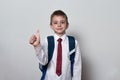 Boy in school uniform shows thumbs up. White background. Children education