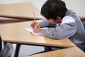 Boy, school and writing in classroom with notebook, studying lesson and learning knowledge at desk. Child, student and Royalty Free Stock Photo