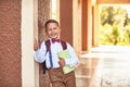 Boy schoolboy holding a textbook leaning against the wall of the school shows a hand sign of approval lifting his finger to the Royalty Free Stock Photo