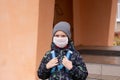 Boy schoolboy walks out of school wearing protective mask