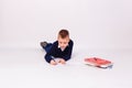 Boy schoolboy writes in notebook on a white background lying down