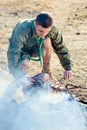 Boy Scout Cooking Sausages on Sticks over Campfire