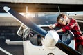 Boy with serious face expression fixing motor of propeller plane outside hangar Royalty Free Stock Photo