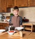 Boy serving Borshch, traditional Russian and Ukrainian soup. Pouring soup into a plate with ladle from pan in kitchen. Royalty Free Stock Photo