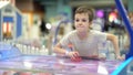 A boy of seven years old enjoys playing air hockey in the playground for entertainment Royalty Free Stock Photo