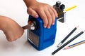 A boy is sharpening his pencil using mechanical sharpener