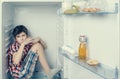 A boy in a shirt and shorts eating a chocolate bar inside a fridge with food and product. Royalty Free Stock Photo