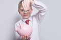 Boy in a shirt and tie puts a coin in a pink piggy bank. Business concept Royalty Free Stock Photo