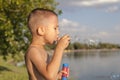 A boy on the shore of the lake blows soap bubbles