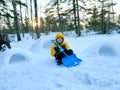 A boy with a shovel built igloos of snow in the backyard in sunset