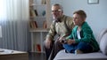 Boy showing grandfather video game, playing with console, happy time together