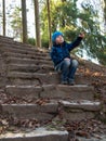 The boy shows his hand sitting on the stairs