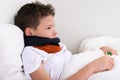 Boy sick in bed neck rewound with scarf Royalty Free Stock Photo