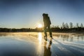 Boy silhouette against of the Sun: a teenager is ice skating on the crystal clear frozen lake - ice surface like big mirror. Low