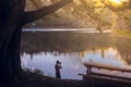 Boy silhouette photographing a beautiful sunset on a lake in to the forest Royalty Free Stock Photo