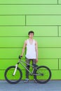 Boy with silver bike stay at green wall background