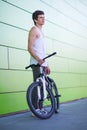 Boy with silver bike stay at green wall background