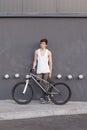 Boy with silver bike stay at grey wall background