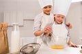 boy with sister in chef hats whisking eggs in bowl at table