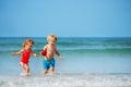 Boy and sister girl run on the sand beach smiling over sea waves Royalty Free Stock Photo