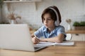 Boy sit at table studying at home online use laptop