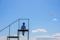 Boy sits against the sky with clouds on the bridge. Background. Dreamer. Fantasy and relaxation teenager child