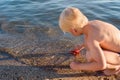 Boy sits on beach and plays with starfish. Vacation with kids Royalty Free Stock Photo